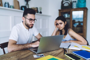 Young people spitting at table and looking at laptop